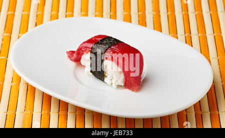 Nigiri thon rouge avec Nori seaweed on white plate.Le poisson cru dans les sushis japonais traditionnel de style. Image horizontale. Banque D'Images