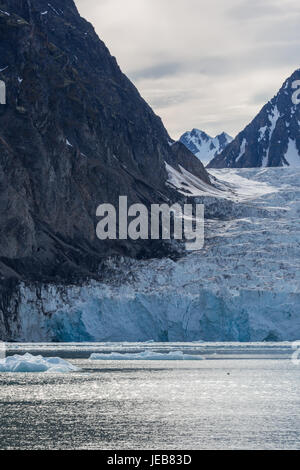 Le bord d'un glacier est recouvert de fragments de roche tombé des falaises rocheuses. Banque D'Images