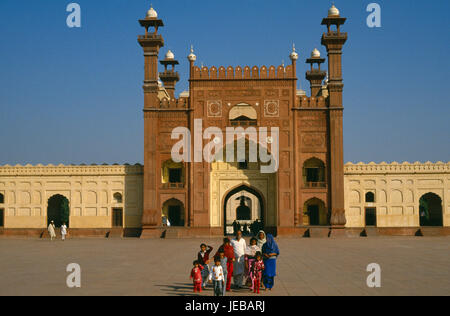 Le Pakistan, Lahore, Punjab, mosquée Badshahi. Comité permanent de la famille dans la petite cour à l'extérieur de l'entrée à la mosquée de Fort Royal construit c. 1673 pendant le règne de l'empereur moghol Aurangzeb. Banque D'Images