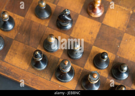 Pièces des échecs en bois ancienne sur un ancien échiquier. Banque D'Images