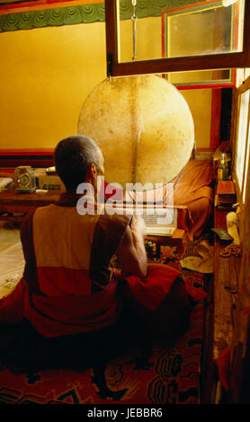 La Chine, Tibet, Shigatse, moine tibétain de chant livre de prières en cellule dans Ta er temple Si également connu sous le nom de Kumbum. Banque D'Images