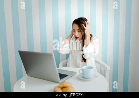 Belle jeune femme inquiète while using laptop Banque D'Images