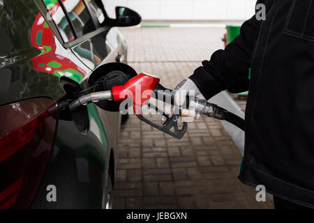 Photo en gros plan de la main et le remplissage de la pompe à carburant voiture à la station service Banque D'Images