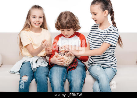 Cheerful friends sitting on couch with popcorn Banque D'Images