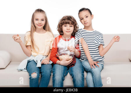 Cheerful friends sitting on couch with popcorn Banque D'Images