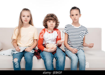 Cheerful friends sitting on couch et eating popcorn Banque D'Images