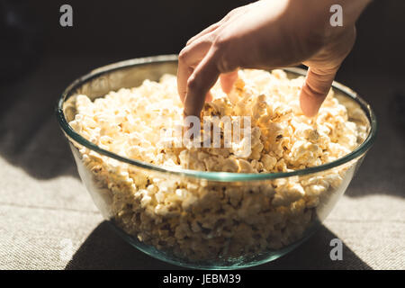 Close up of main humaine en tenant un bol en verre de popcorn Banque D'Images