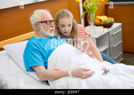 Grand-père dans les lunettes et petite-fille à l'hôpital en comprimés à Banque D'Images