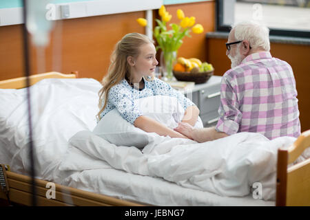 Grand-père et sa petite-fille assis sur lit d'hôpital et à la recherche à l'autre Banque D'Images