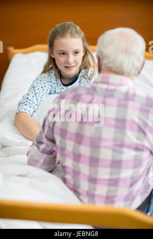 Grand-père et sa petite-fille assis sur lit d'hôpital et à la recherche à l'autre Banque D'Images