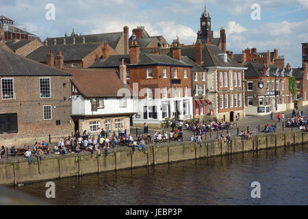 Les gens assis à l'extérieur des pubs sur journée ensoleillée au bord de la rivière Ouse, York, North Yorkshire Banque D'Images