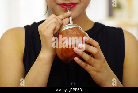 Hispanic woman drinking mate à partir de la tasse traditionnelle à l'aide de paille de métal, de l'Amérique du Sud boisson populaire. Banque D'Images