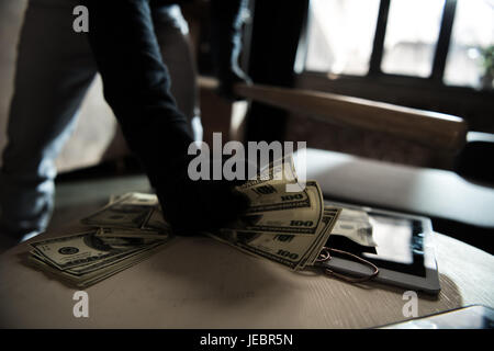 Close-up vue partielle de cambrioleur voler l'argent de table, chambre scène de vol Banque D'Images