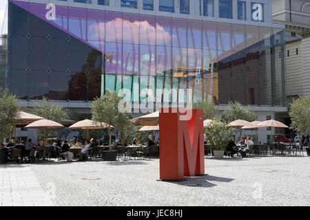 Germany, Bavaria, Munich, l'espace Marstall, St. d'art, 'M', street cafe, visiteur, Haute-Bavière, carré, rue, café, à l'extérieur, parasols, les gens, les bâtiments, la façade de verre, miroir, nuage, lettre, art, sculpture, rouge, Banque D'Images