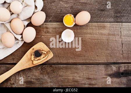 Farm Fresh organic brown les oeufs de poule de poules avec un vieux antique en bois d'olivier spatule sur un fond de bois rustique. Un œuf fêlé Banque D'Images