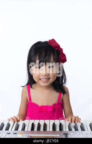 Chinois asiatique petite fille jouant du clavier du piano électrique isolé en fond blanc. Banque D'Images