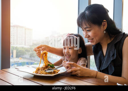 Chinois asiatique mother and daughter eating spaghetti bolognese au restaurant. Banque D'Images