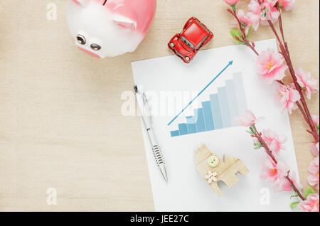 Vue de dessus de bureau d'entreprise concept. Économiser de l'argent avec tracé résumé Bois Maison et voiture aussi réveil sur planche en bois.La belle fleur rose wit Banque D'Images