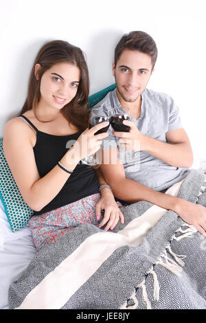 Beau jeune couple drinking wine in bed. À l'intérieur. Banque D'Images