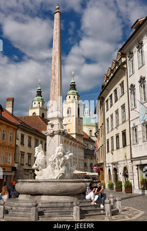 Les touristes à l'Robba Fontaine des trois rivières de la place de la ville de Ljubljana, capitale de la Slovénie avec St Nicholas Church Cathedral Banque D'Images