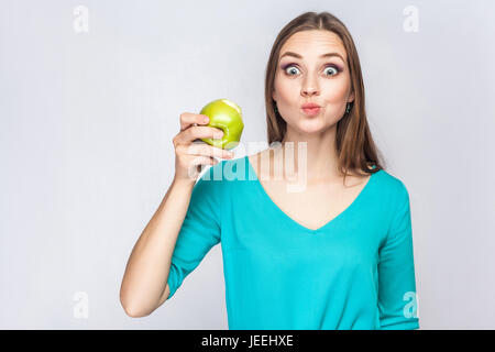 Belle jeune femme avec des taches de rousseur et green dress holding et délicieux et looking at camera avec de grands yeux surpris. studio shot, isolé sur l Banque D'Images