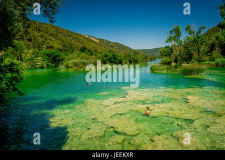 Un couple nager en dessous de la cascade Skradinski buk au Parc National de Krka en Croatie Banque D'Images