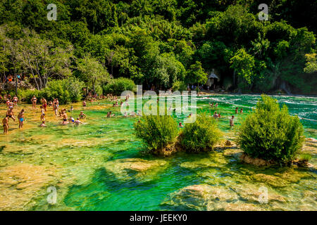 Un couple nager en dessous de la cascade Skradinski buk au Parc National de Krka en Croatie Banque D'Images