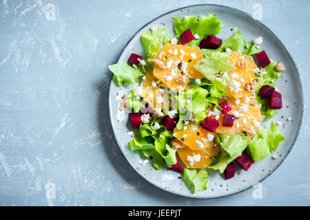 Avec salade de betterave rouge, l'orange, les noix et le fromage feta sur fond bleu avec copie espace. Maison saine d'été végétarien salade de betteraves. Banque D'Images