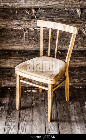 Vintage chaise en bois se trouve près de l'ancien log mur de la maison. Banque D'Images