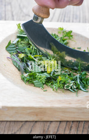 Demi-lune Mezzaluna herb chopper et chopping board une sélection d'herbes. UK Banque D'Images