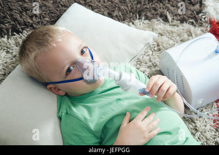 Boy making inhalation avec le nébulisateur à domicile. L'inhalation Inhalateur d'asthme de l'enfant malade à vapeur nébuliseur concept toux Banque D'Images