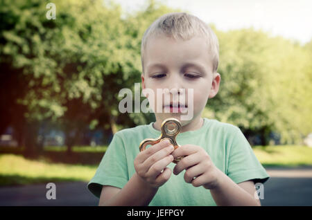 Petit garçon avec un spinner fidget extérieur. spinner fidget le stress de l'enfant tdah attention concept fad boy Banque D'Images