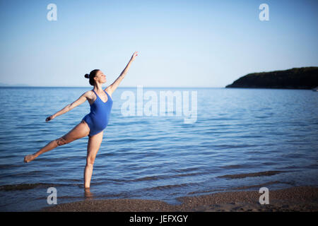 Jeune femme enceinte dans la méditation de yoga on beach Banque D'Images