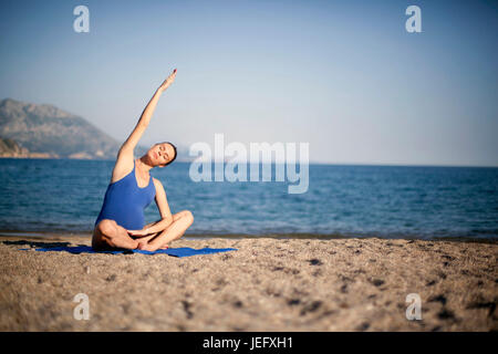 Jeune femme enceinte dans la méditation de yoga on beach Banque D'Images