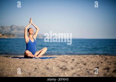 Jeune femme enceinte dans la méditation de yoga on beach Banque D'Images