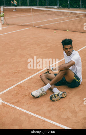 Jeune homme en uniforme de sport se trouve sur le terrain d'un court de tennis Banque D'Images