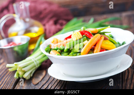 Mélanger les légumes dans le bol et sur une table Banque D'Images