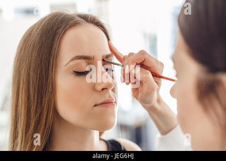 Belle femme créer une forme de sourcils à l'aide de crayon pinceau Banque D'Images