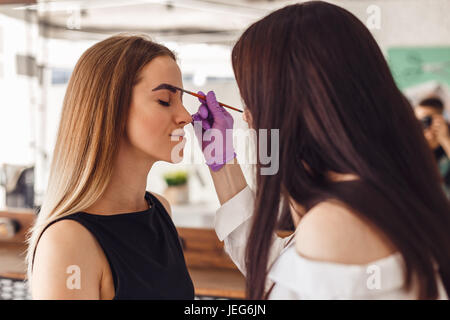 Maquilleur applique de la peinture sur les sourcils de henné dans un salon de beauté. Banque D'Images