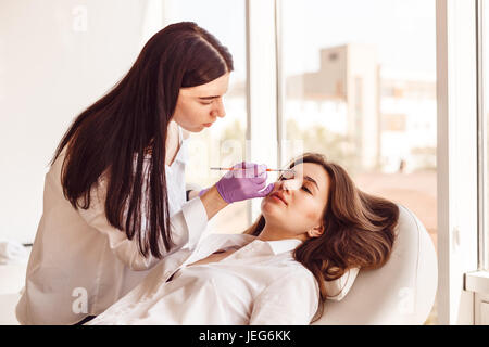 La clientèle féminine est allongé sur une table pendant blanc et correction de style sourcil. Banque D'Images