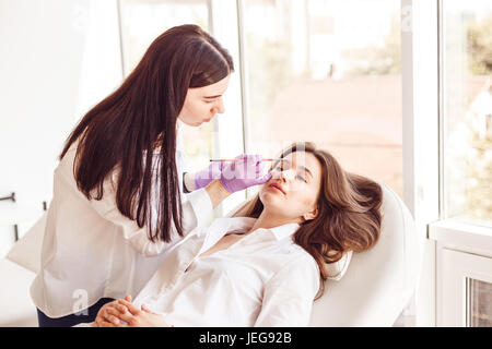 La clientèle féminine est allongé sur une table pendant blanc et correction de style sourcil. Banque D'Images