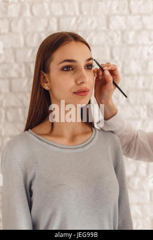 Belle femme et créer une forme de cosmetologist sourcils à l'aide pinceau cosmétique Banque D'Images