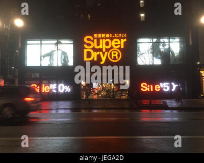 New York City - 20 janvier 2017 : SuperDry, détaillant de vêtements japonais, à Midtown New York la nuit après la pluie. Feux arrière de voitures des véhicules qui passent. Banque D'Images