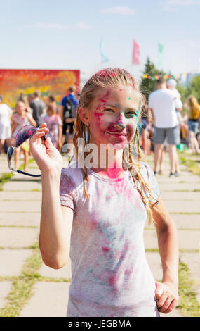 Jeune fille joyeuse arrosée de peinture sèche au festival de peinture Banque D'Images