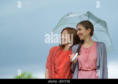 Deux femmes marchant park dans la pluie et de parler. L'amitié et les gens de la communication. Banque D'Images