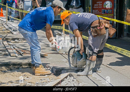 Les travailleurs de la construction sur la 37e Ave. à Jackson Heights, Queens ciment coupe remet en état un trottoir. Banque D'Images