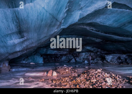 Un homme se tient à l'intérieur d'une immense caverne de glace au terminus de l'Augustana Glacier dans la chaîne de l'Alaska en hiver ; Alaska, États-Unis d'Amérique Banque D'Images