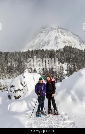 Deux femmes de la raquette sur une piste couverte de neige avec la neige en arrière-plan ; la montagne de Kananaskis, Alberta, Canada Banque D'Images