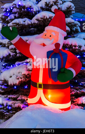 Gonflé lumineux Père Noël Décoration de Noël avec des lumières de Noël sur un arbre couvert de neige ; Calgary, Alberta, Canada Banque D'Images