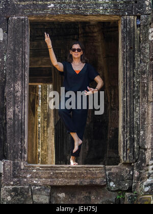 Une femme s'sitting une ouverture de temple Bayon, Angkor Thom ; Krong Siem Reap, la Province de Siem Reap, Cambodge Banque D'Images